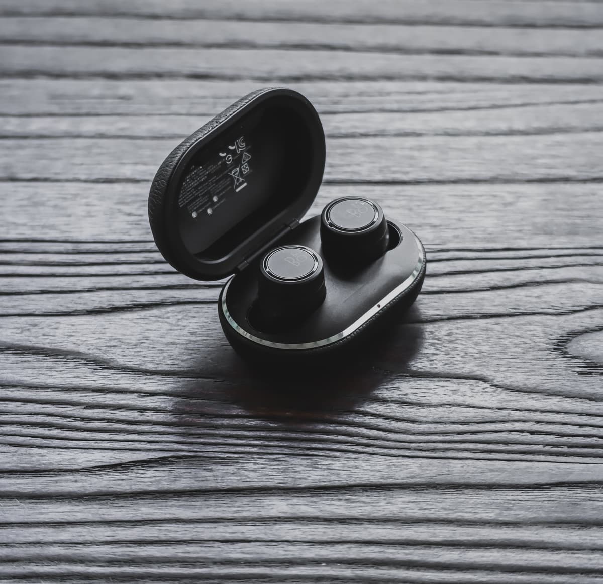 True wireless earbuds in an open charging case on a wooden surface