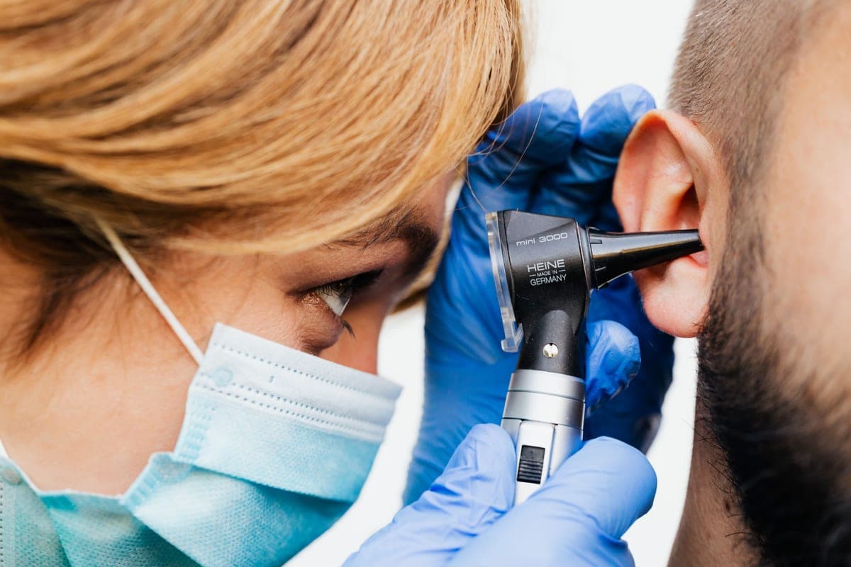 A doctor examining a patient's ear with an otoscope
