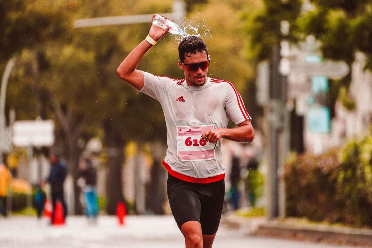 A marathon runner pouring water over his head to cool down