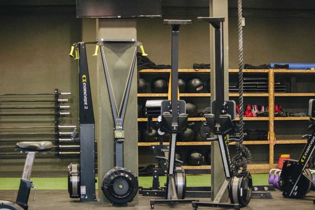 A gym floor with rowing and ski machines, weights and ropes