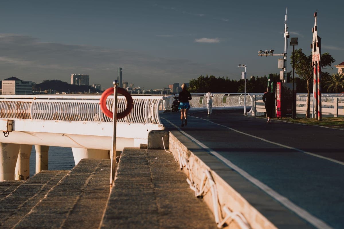 A jogger on a waterfront path at sunrise