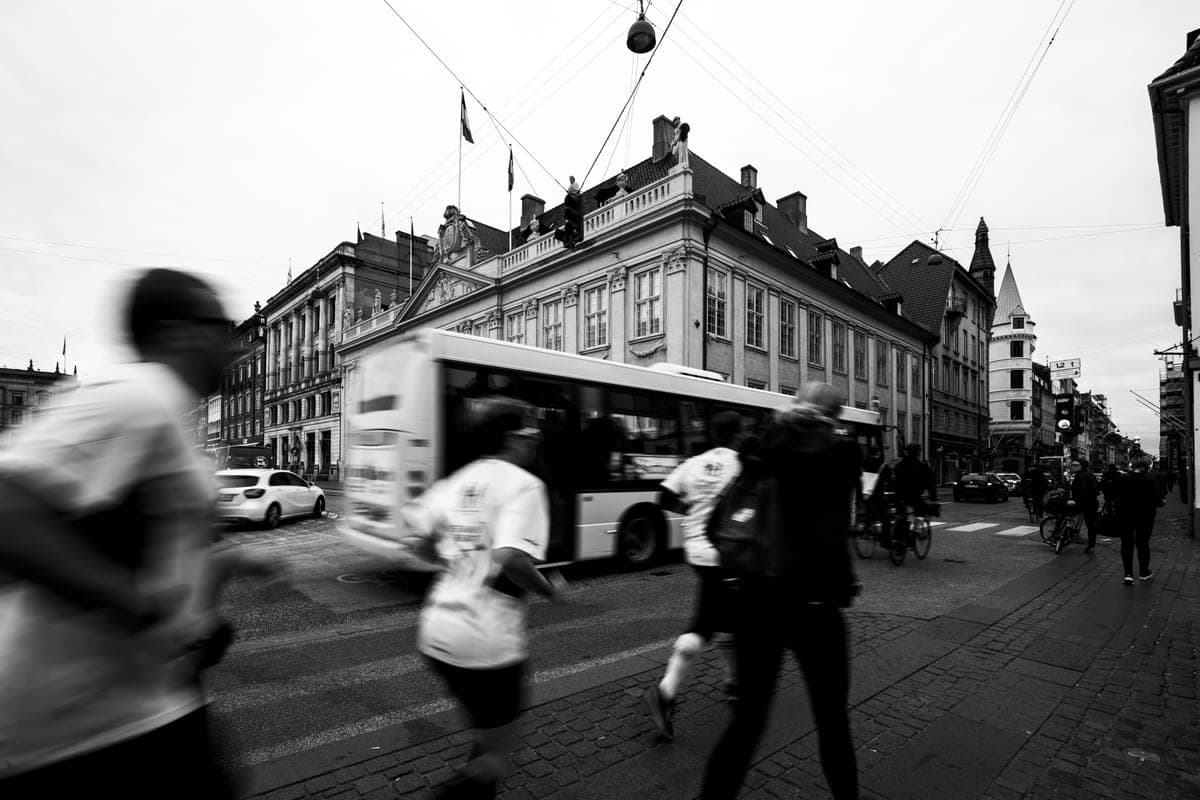 A black-and-white city scene with joggers and pedestrians in motion