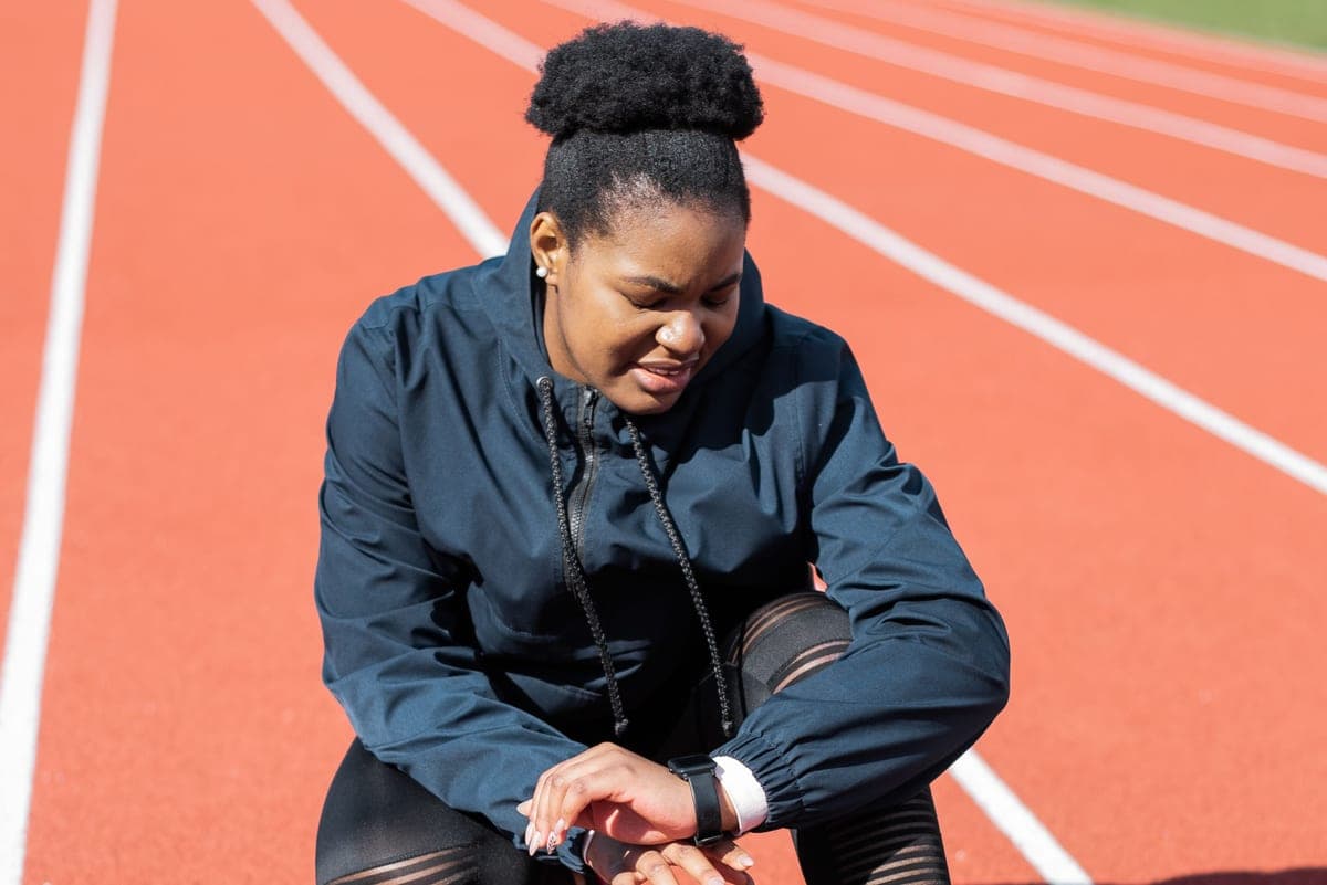 A woman on a running track checking her smartwatch after a workout